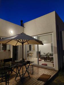 a patio with an umbrella on a wooden deck at Habitación en Casa de mar in Quequén
