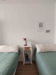 a bedroom with two beds and a table with a lamp at Habitación en Casa de mar in Quequén