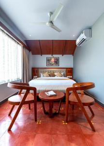 Schlafzimmer mit einem Bett, einem Tisch und Stühlen in der Unterkunft Palcastle Regency in Palakkad