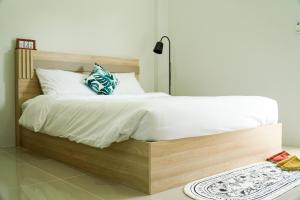 um quarto com uma grande cama de madeira com lençóis brancos em เมตตา เรสซิเด้นซ์ - Metta Residence em Ban Dam Phra