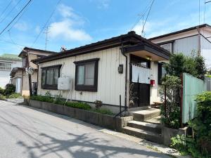 a small white house on the side of a street at 八戸ゲストハウス トセノイエ / Hachinohe Guest House Tosenoie in Hachinohe
