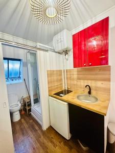 y baño con lavabo, armarios rojos y aseo. en Attractive 20 m in the heart of city en Neuilly-sur-Seine
