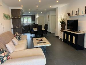 Una sala de estar con un sofá, un televisor y una mesa. en Beach Bungalow, en Málaga