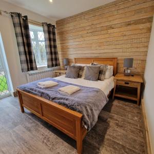 a bedroom with a large bed with a wooden wall at Brookside Cottages in Ingoldmells