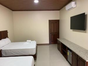 um quarto de hotel com duas camas e uma televisão de ecrã plano em Orquideas Boutique Hotel em La Fortuna