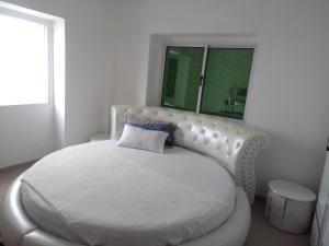 una camera bianca con un letto bianco e un cuscino blu di Residencial beira mar Benguela a Benguela
