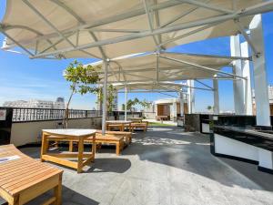 un patio con mesas y bancos en el techo en Placid Studio close to Dubai Miracle Garden en Dubái