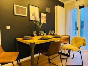 ein Esszimmer mit einem Tisch mit Stühlen und Weingläsern in der Unterkunft Klassen Stay - Designer Apartment für 6 - Zentral - 2x Kingsize in Essen