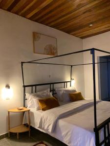 um quarto com uma cama grande com lençóis brancos e almofadas amarelas em Natoose Lodge em Saint-Louis