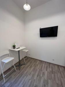 a room with a table and a tv on a wall at Goldensun Apartment in Budapest