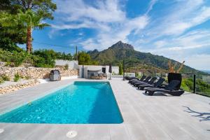 a swimming pool with chairs and a mountain in the background at Calpeview II Luxury Villa By Calpitality in Calpe