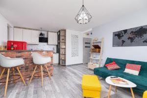 a living room with a green couch and a kitchen at Apartments Cracow Czeczow by Renters in Kraków