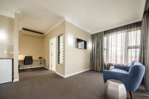 Cowra Services Club Motel في كورا: غرفة معيشة مع أريكة زرقاء ونافذة