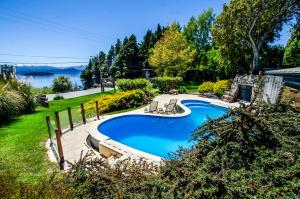 a swimming pool in a yard next to a lake at Nido del Cóndor Hotel & Spa in San Carlos de Bariloche