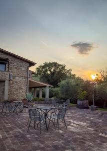 un gruppo di tavoli e sedie con il tramonto sullo sfondo di Santa Maria Degli Ancillotti a Petrignano