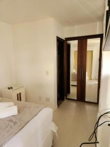 a white bedroom with a bed and a mirror at MODERNO FLAT LAKE SIDE in Brasilia