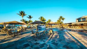 a swimming pool with tables and chairs and umbrellas at MODERNO FLAT LAKE SIDE in Brasília