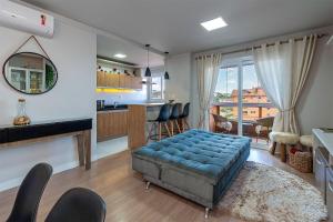 a living room with a blue ottoman and a kitchen at Rua Coberta de Canela @stayhousetemporada in Canela