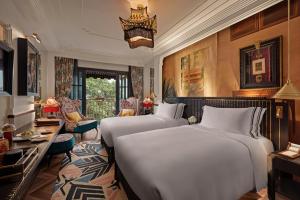 a bedroom with two beds and a living room at Capella Hanoi in Hanoi