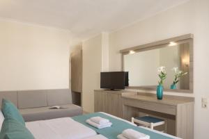 Habitación de hotel con cama, escritorio y TV. en Central Hersonissos Hotel en Hersonissos