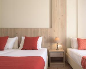 two beds with red and white pillows in a room at Central Hersonissos Hotel in Hersonissos