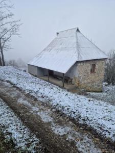 um edifício de pedra com um telhado sobre um campo coberto de neve em Ethno guesthouse Tara em Mojkovac
