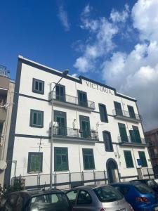 トッレ・アンヌンツィアータにあるVictoria Apartmentsの前に車が駐車されている白い建物