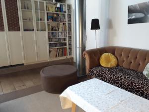 een woonkamer met een bank, een kruk en een boekenplank bij Chez Séverine & Edward in Sainte-Vertu