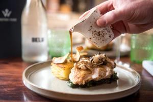 a person pouring sauce on a piece of food on a plate at Knoll Tower in Shifnal