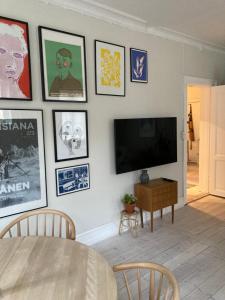 uma sala de estar com uma televisão de ecrã plano numa parede com fotografias em 400 m from metro modern cozy apartment em Copenhague
