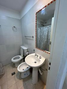 ein Badezimmer mit einem WC, einem Waschbecken und einem Spiegel in der Unterkunft Apartamentos El Fortín in San Salvador de Jujuy