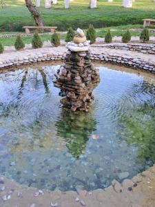 a rock fountain in a pond in a park at Mala farma Nani in Visoko