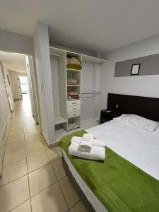 a bedroom with a bed with a green blanket at Apartamentos El Fortín in San Salvador de Jujuy