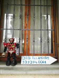 un robot de juguete sentado en un alféizar junto a una señal en B&B Des Artistes, en Borzano