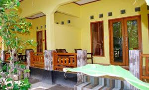 Casa con porche con cama y sillas en Matahari Bungalow 3, en Gili Air