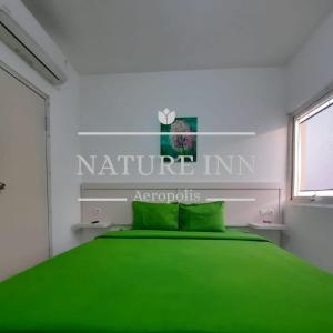 ein Schlafzimmer mit einem grünen Bett und einem Schild mit einem naurillen-Gasthof in der Unterkunft NATURE INN Aeropolis AR3 in Tangerang