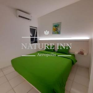 a bedroom with a green bed with a sign on it at NATURE INN Aeropolis AR3 in Tangerang