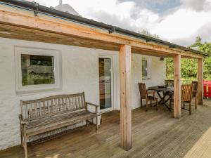 porche de madera con banco y mesa en Gun Powder Cottage, en Tighnabruaich
