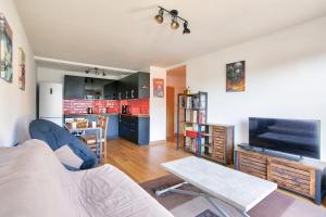 a living room with a couch a table and a tv at Vacances au pied de la plage du Val-André in Le Val-André