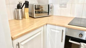 a kitchen with a wooden counter top with a microwave at Cosy 1 Bed, Wembley in London