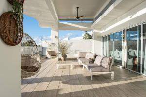 ein Wohnzimmer mit einem Sofa und Stühlen auf einer Terrasse in der Unterkunft Vistamar Villa 5BDR Private Waterfront Home Pool 