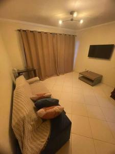 a living room with a couch and a tv at Ótima Casa com Piscina, Sauna e Churrasqueira in Cabo Frio