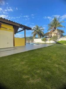 um quintal de uma casa com piscina e palmeiras em Ótima Casa com Piscina, Sauna e Churrasqueira em Cabo Frio