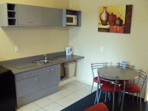 a small kitchen with a table and a sink at At The Rocks Motorlodge in Napier