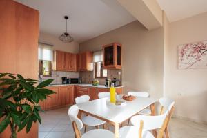 a kitchen with a white table and white chairs at Maroulas Villas Ioanna & Stavros, stunning views, By ThinkVilla in Maroulás