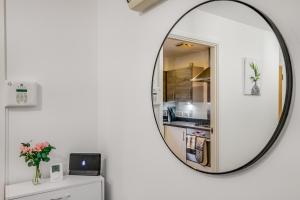 a round mirror on a white wall with a kitchen at 3 bedroom detached house free car park close to town airport in Luton