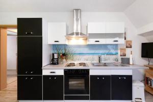 a kitchen with black and white cabinets and a stove at Wuddisferienwohnug in Nordleda