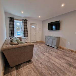 a living room with a couch and a flat screen tv at Brookside Cottages in Ingoldmells