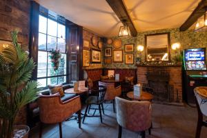 a restaurant with tables and chairs and a fireplace at Rockingham Arms By Greene King Inns in Wentworth