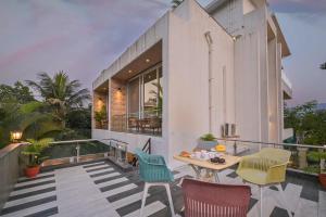 Cette maison dispose d'un balcon avec une table et des chaises. dans l'établissement Elegant Villa By Tropicana Stays, à Lonavala